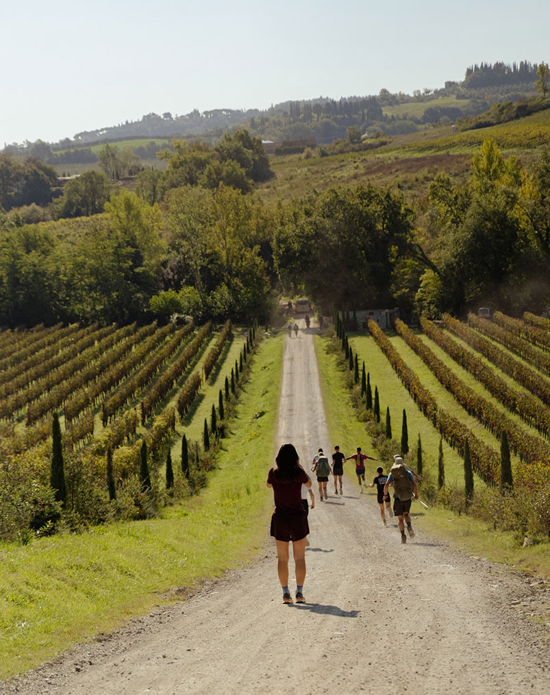 Two runners on a dirt road through Tuscan hills